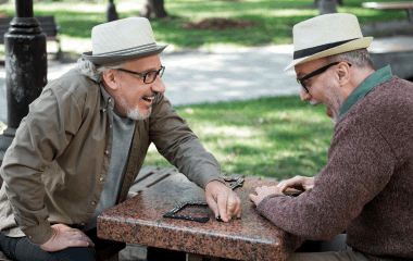 Two men playing dominoes at a park.