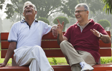 Two men laughing on park bench.