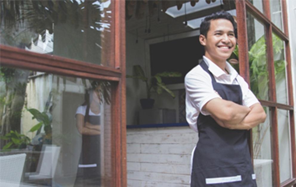 Business man standing in doorway to his cafe.