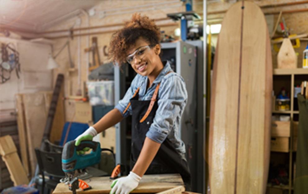 Woman using a saw in a workshop.