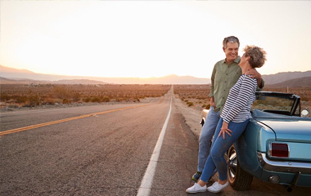 Man and woman leaning against classic car.