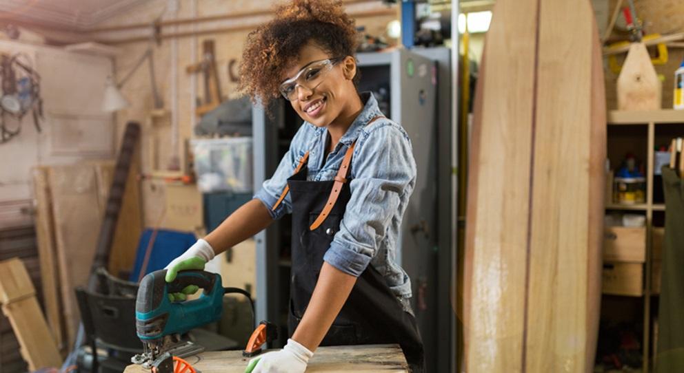 Woman sawing wood in a workshop.