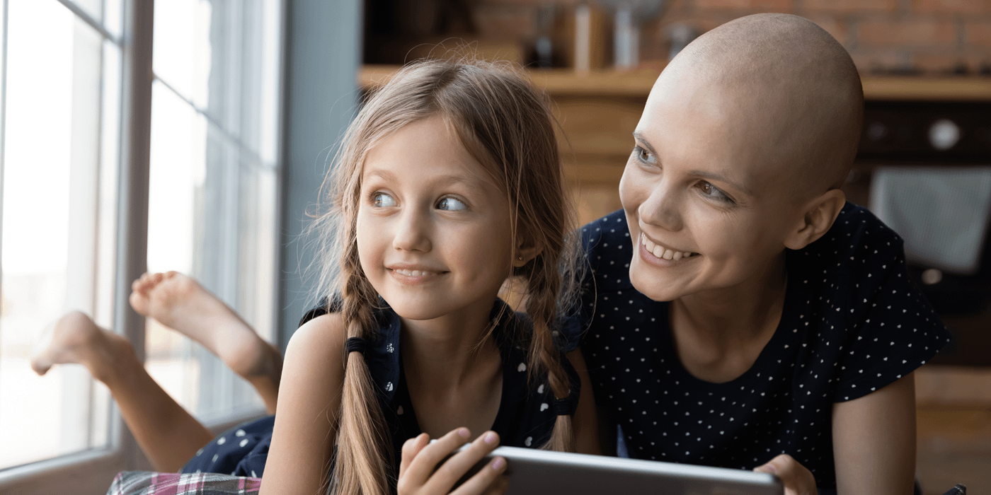 Woman, with cancer, and daughter looking out the window, smiling.