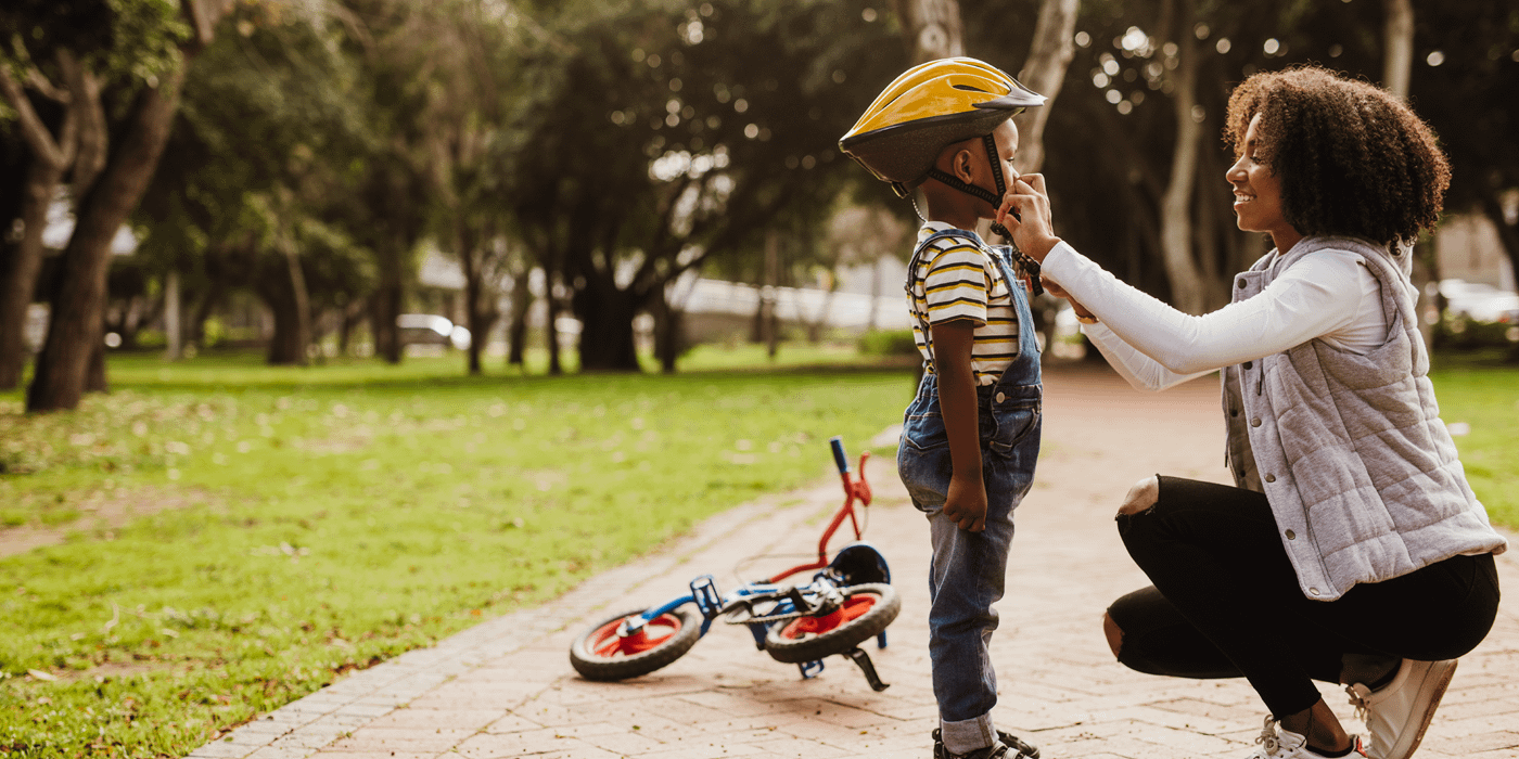 Mother putting on son's helmet on for a bike ride.