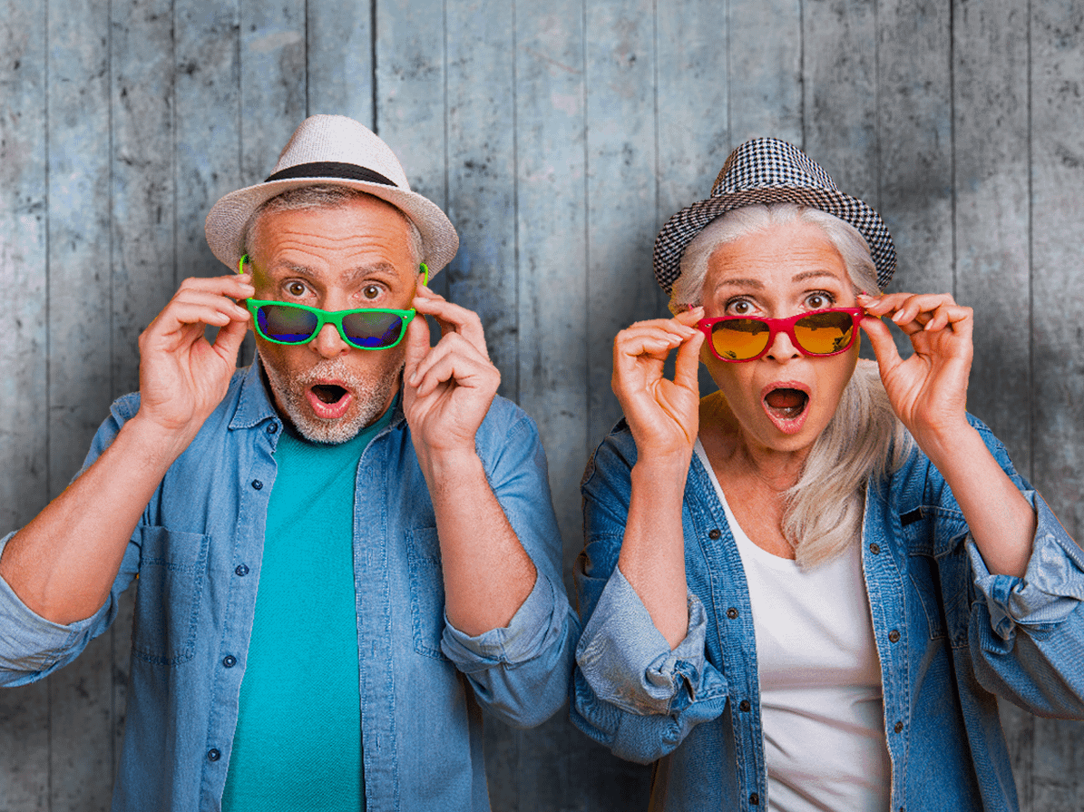 A man and a woman looking over pairs of sunglasses.